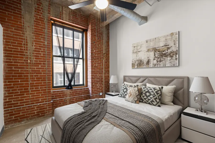 Bedroom framed by heavy brick and a tall industrial window