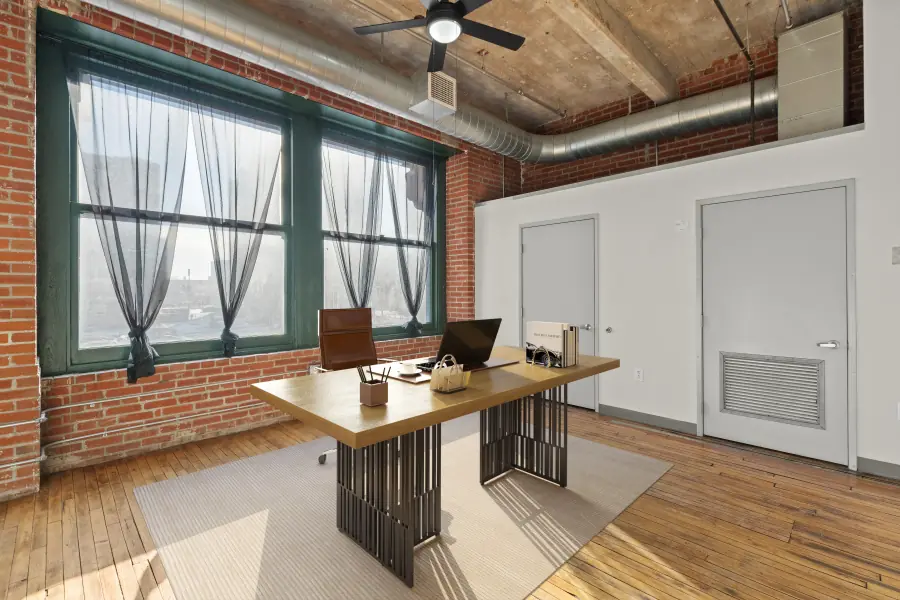Home office corner with brick walls, hardwood floors and exposed ductwork