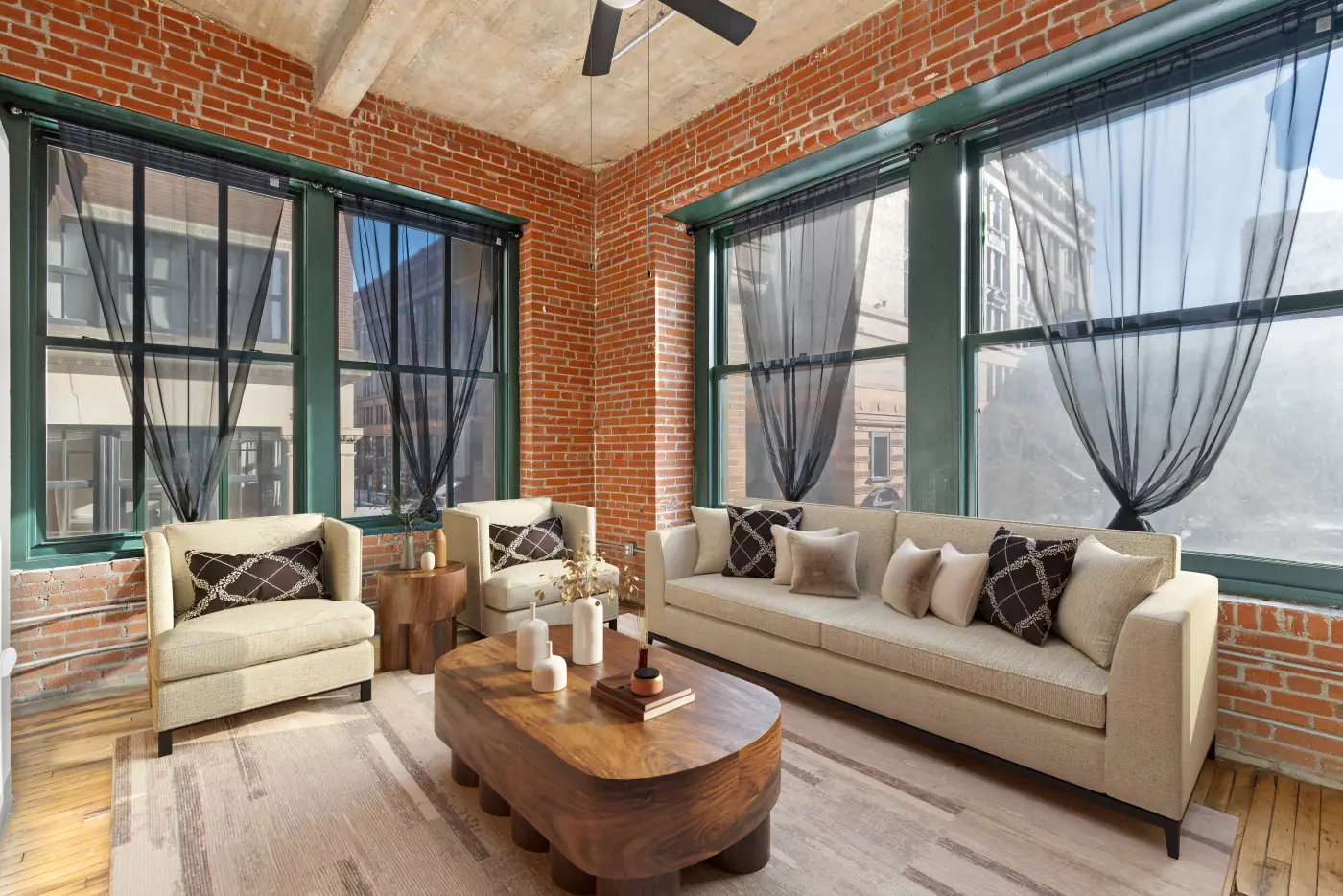 Corner living room framed by tall windows and exposed brick